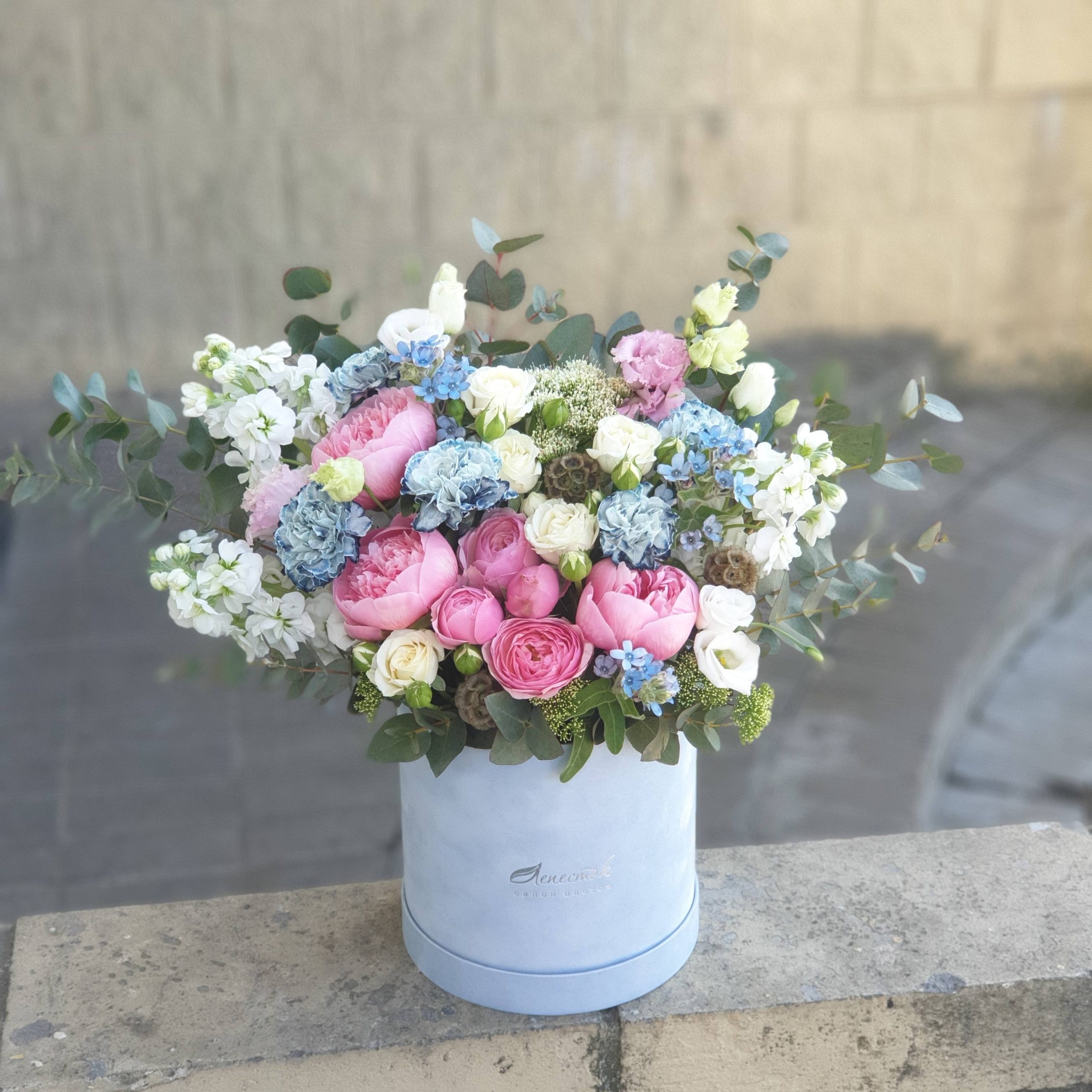 Бархатный цилиндр из голубых диантусов, розовых пионов и ароматной маттиолы